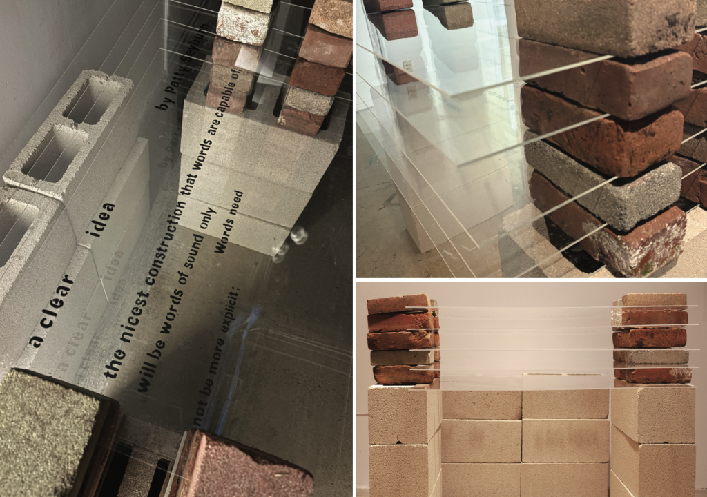 A close-up of transparent or acrylic panels etched or printed with fragmented poetic text, including phrases like 'a clear idea' and 'the nicest construction.' The panels are layered, creating a sense of depth, with concrete blocks visible in the background.